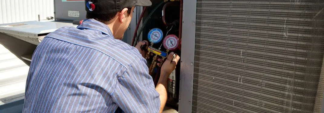 HVAC technician servicing a condenser unit in Laurens